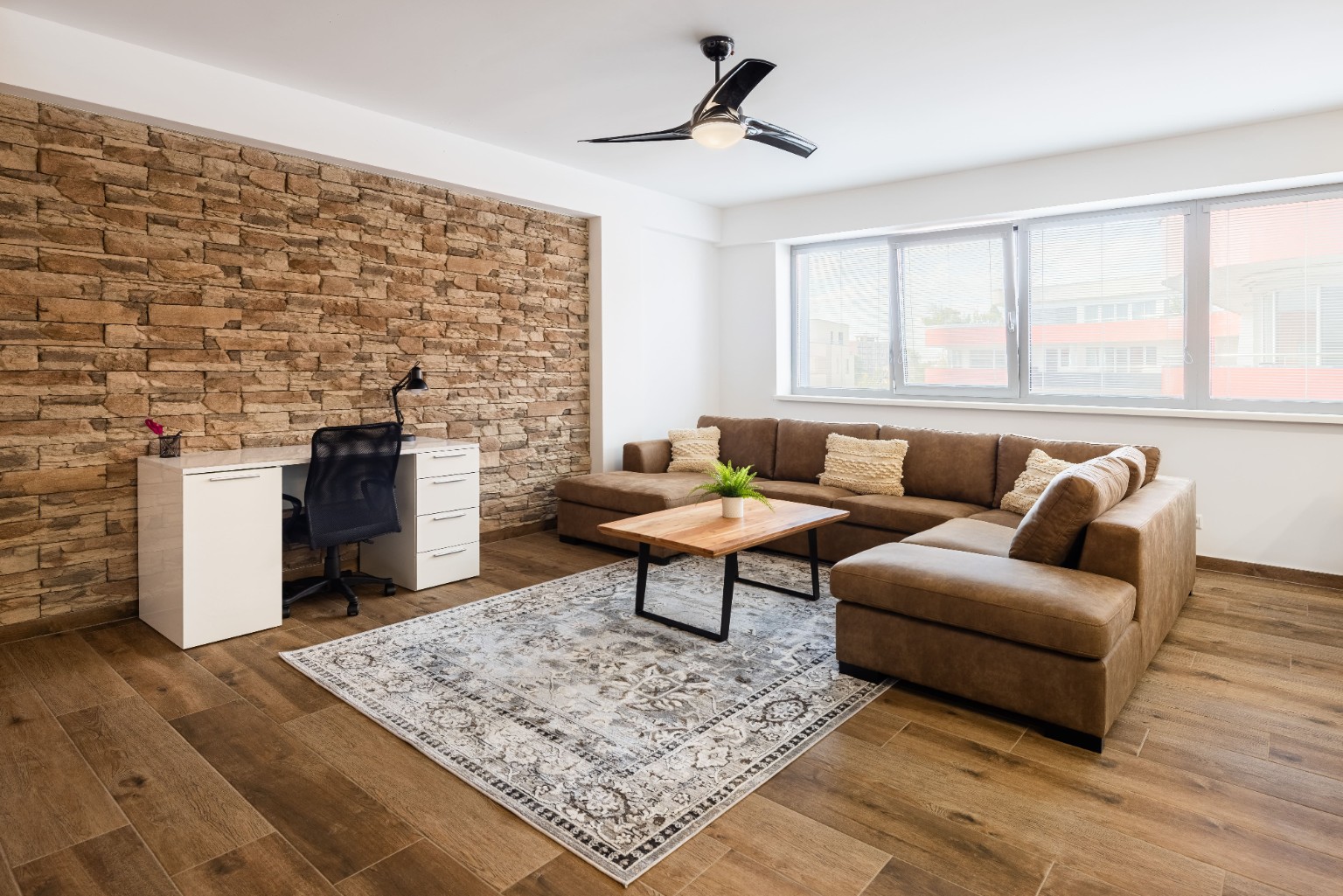 City Center Gallery living room with stone wall, brown sofa, desk and office chair