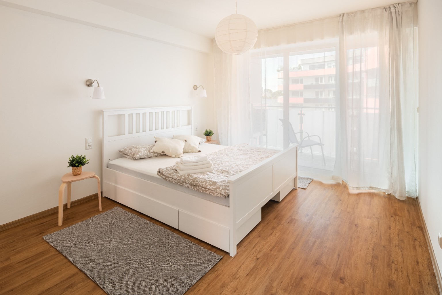 Bright bedroom with a large white bed and balcony access