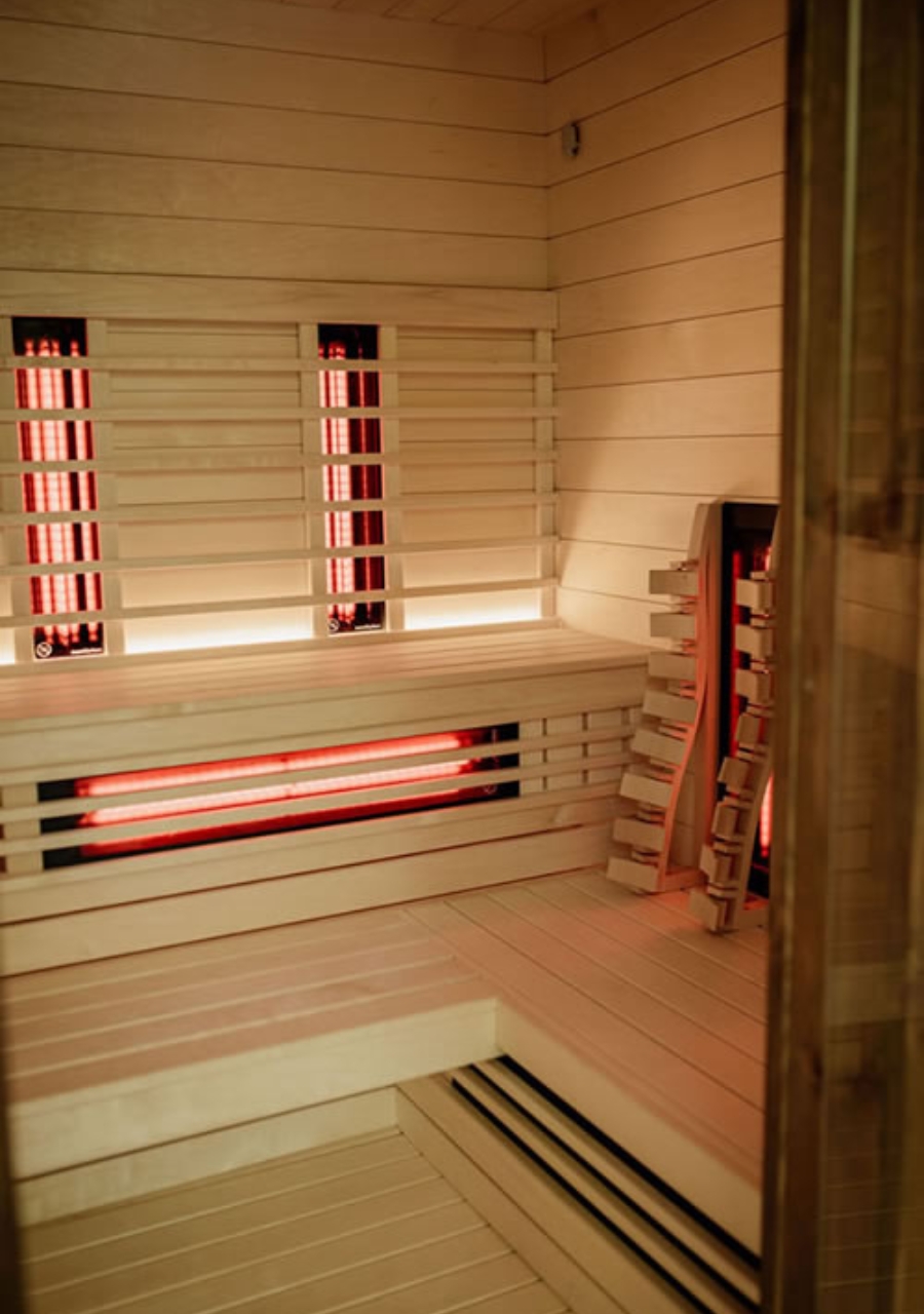Wood-lined sauna with benches and red heating panels.